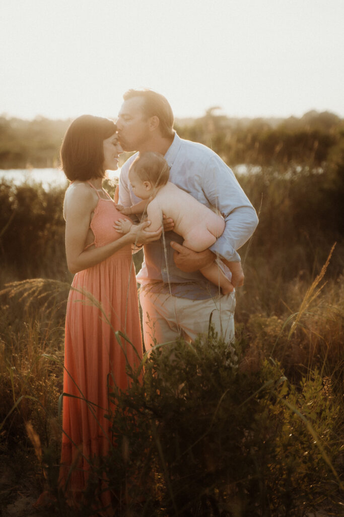 Family Photography, mom and dad holding naked baby in a field