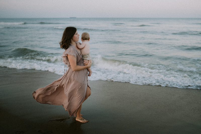 Family photography, mom holds baby while walking on the beach